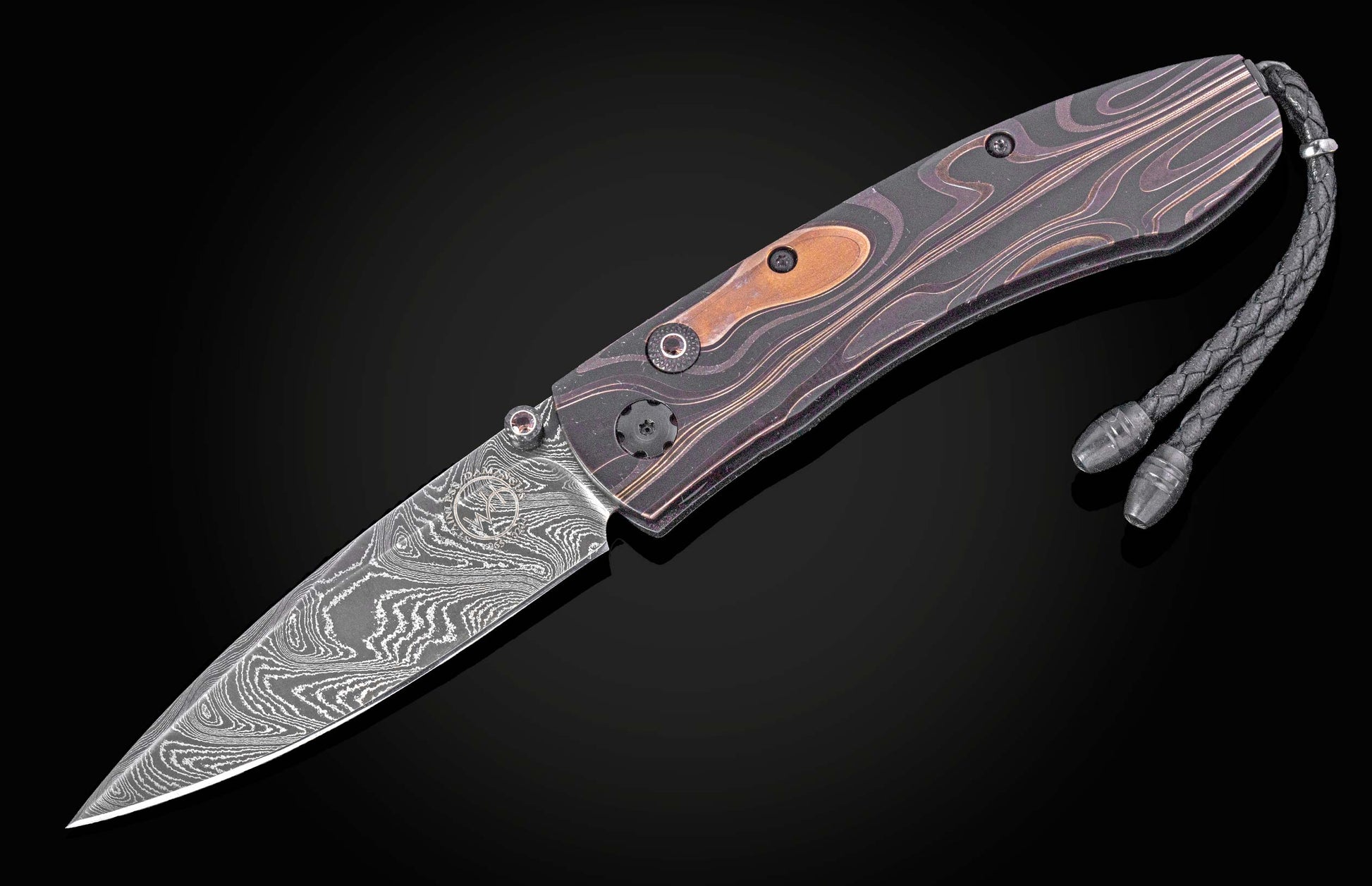 Dark patterned folding knife with damascus steel blade and wood inlay handle, featuring braided lanyard, side view on black background
