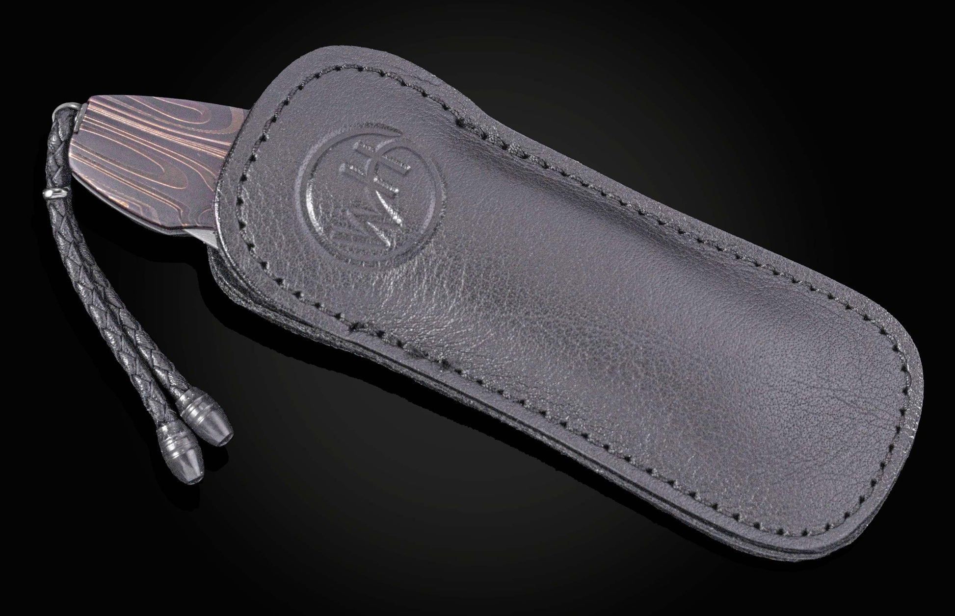 Dark Damascus steel knife with dark leather sheath by B05, featuring embossed logo and braided cord, side view on black background