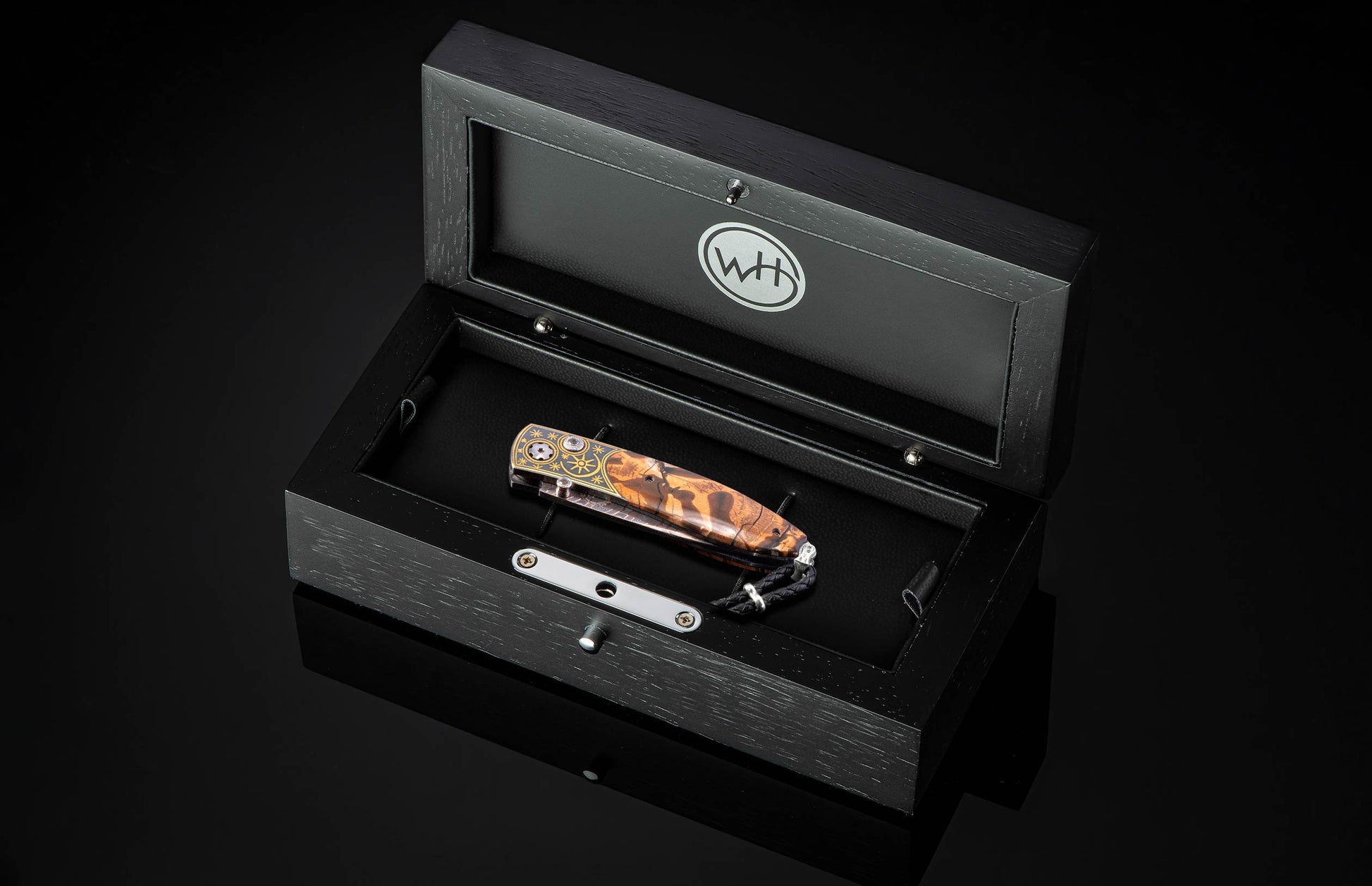Black open box with a pocket knife inside on a black background
