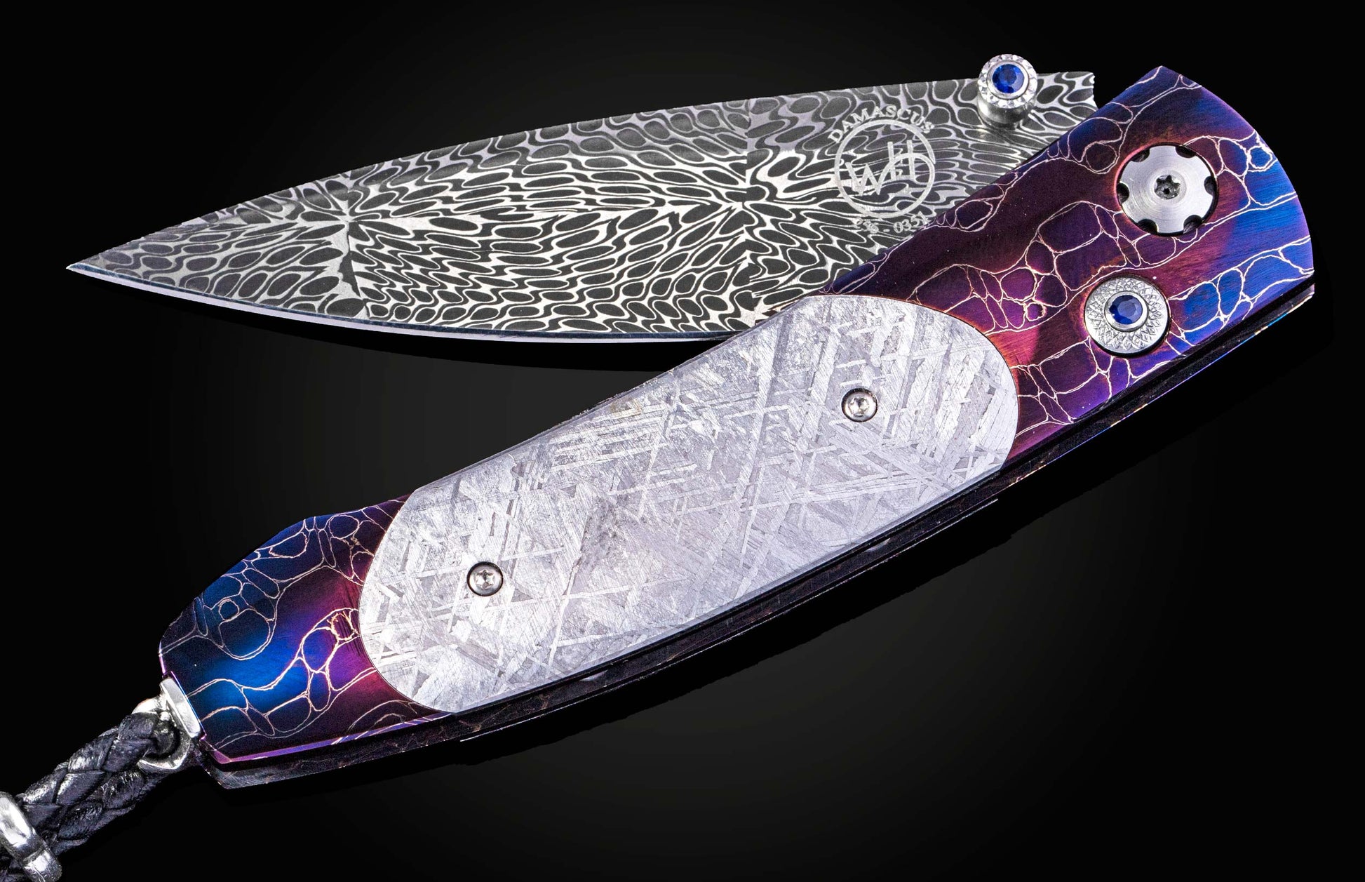 William Henry knife with a colorful handle and engraved blade on a black background