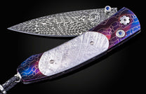 William Henry knife with a colorful handle and engraved blade on a black background