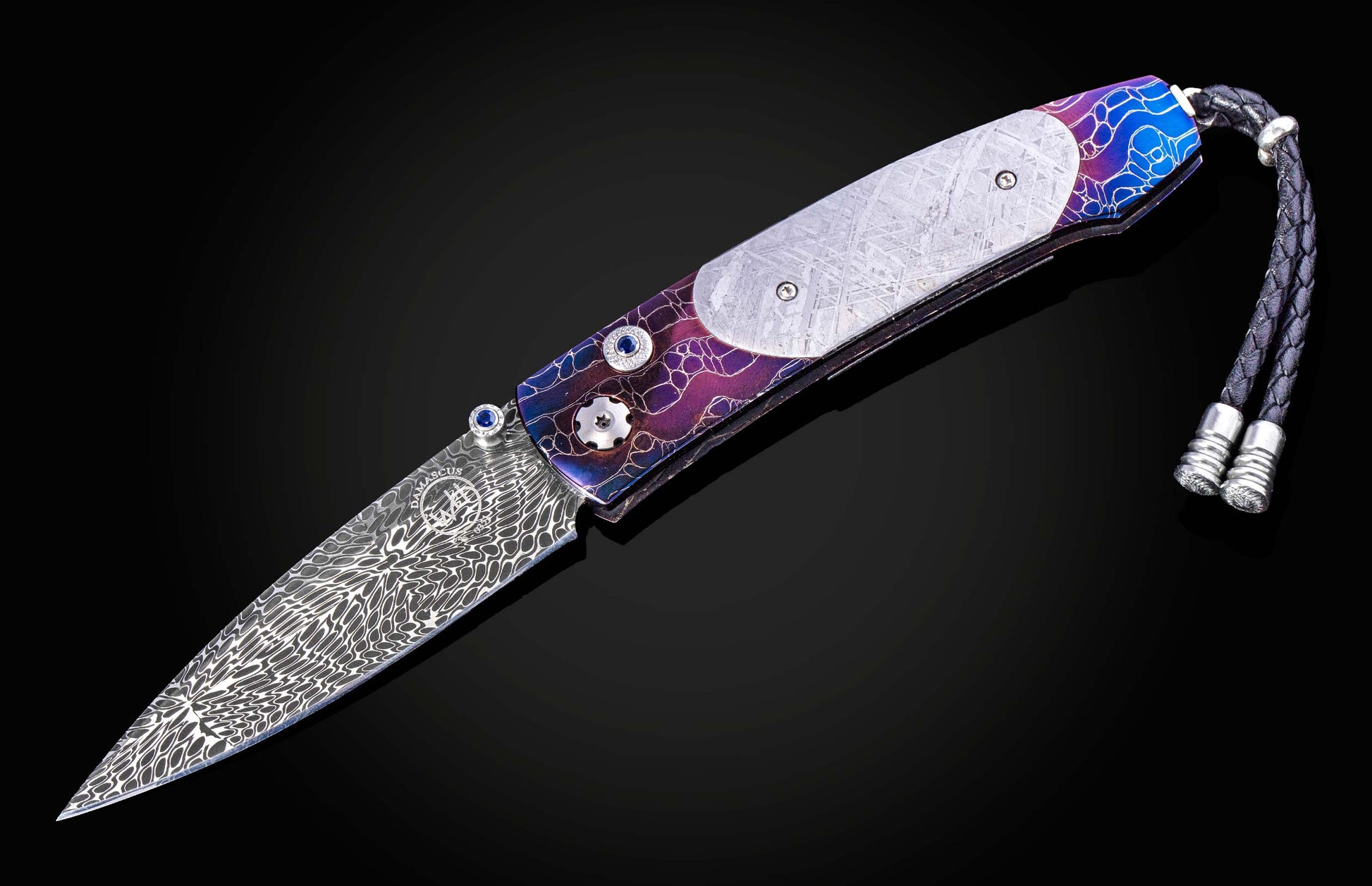 William Henry knife with a colorful handle and engraved blade on a black background