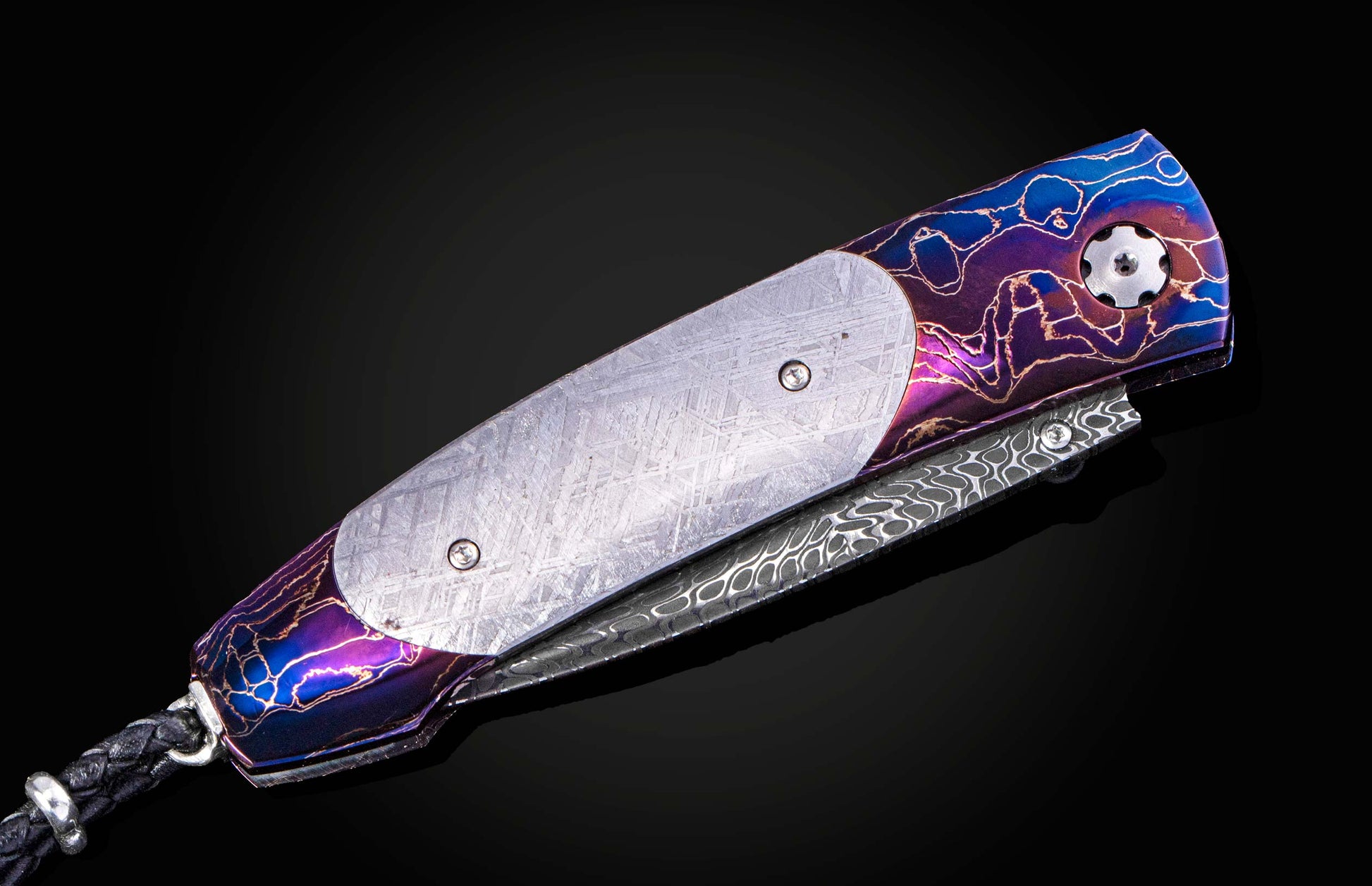 William Henry knife with a colorful handle and engraved blade on a black background