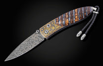 Decorative knife with a fossil mammoth tooth and gold handle on a black background displayed fully open