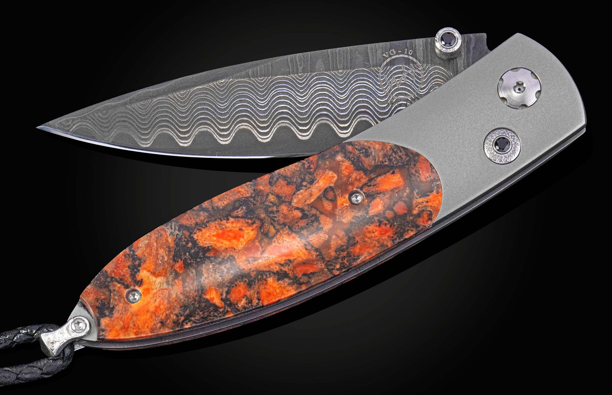 Folding knife with a Damascus steel blade and orange and black handle on a dark background