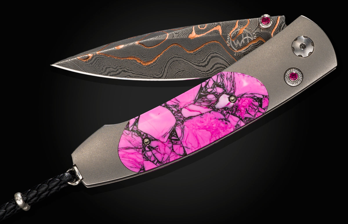 Damascus steel folding knife with vibrant pink gemstone inlay and ruby accents, by B05 Resilience, displayed open on black background