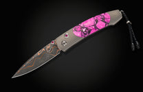 Luxury damascus steel knife with vibrant pink stone handle and ruby accents, featuring braided black lanyard, side view on dark background