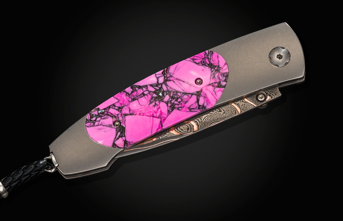 Folding knife with vibrant pink and black marbled handle, brushed titanium frame, Damascus steel blade, side view on black background