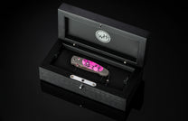 Luxury folding knife with vibrant pink marbled handle and polished silver hardware by W+H, displayed in a sleek black presentation box.