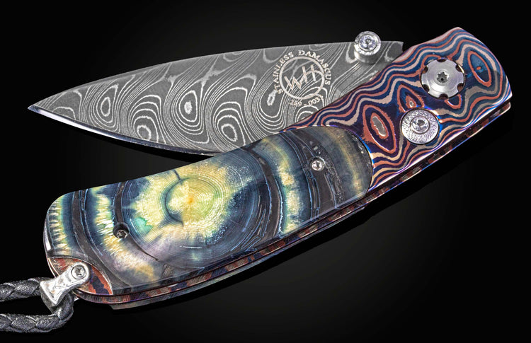 Folding knife with Wave Mokume, fossil mammoth tusk, and a damascus blade on a black background