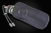 Folding knife with Wave Mokume, fossil mammoth tusk, and a damascus blade on a black background