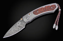 Folding knife with wooden handle and damascus blade on a black background