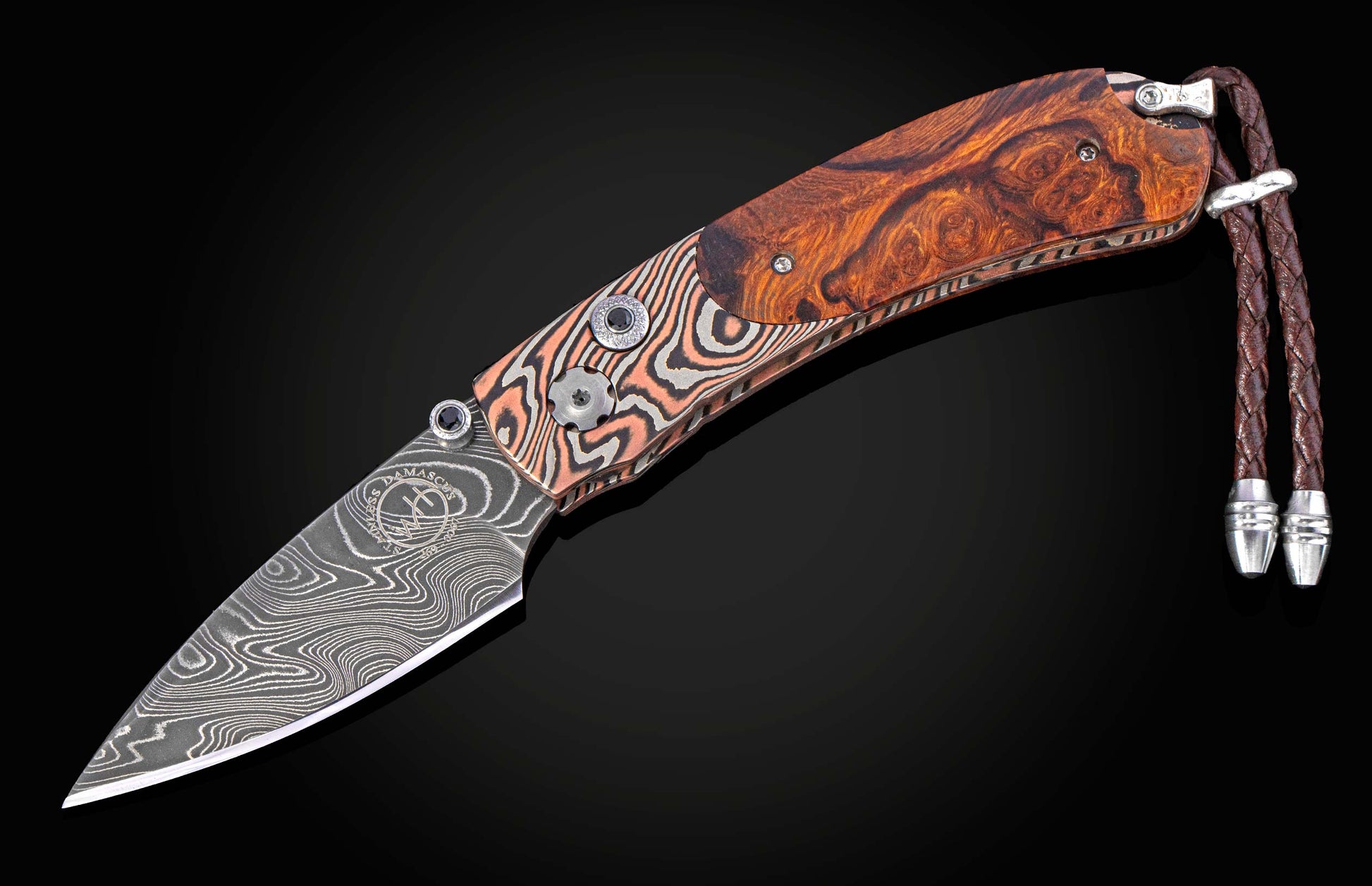 Folding knife with a decorative blade and desert ironwood handle on a black background with the blade open