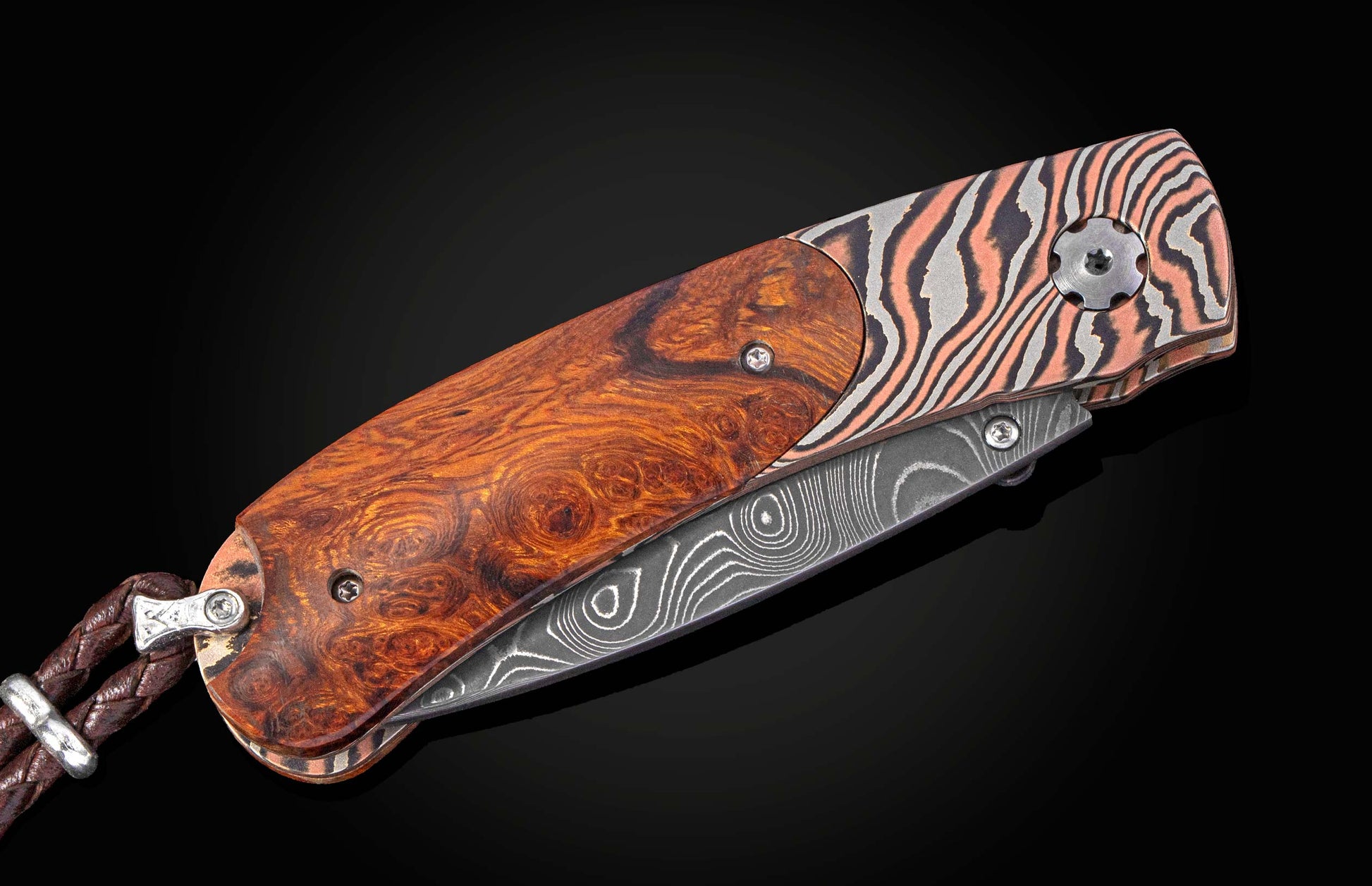 Folding knife with a decorative blade and desert ironwood handle on a black background with the blade closed