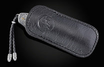 Decorative knife with intricate patterns in a leather case on a dark background