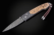 Folding knife with damascus blade and fossil walrus bone scales on a black background