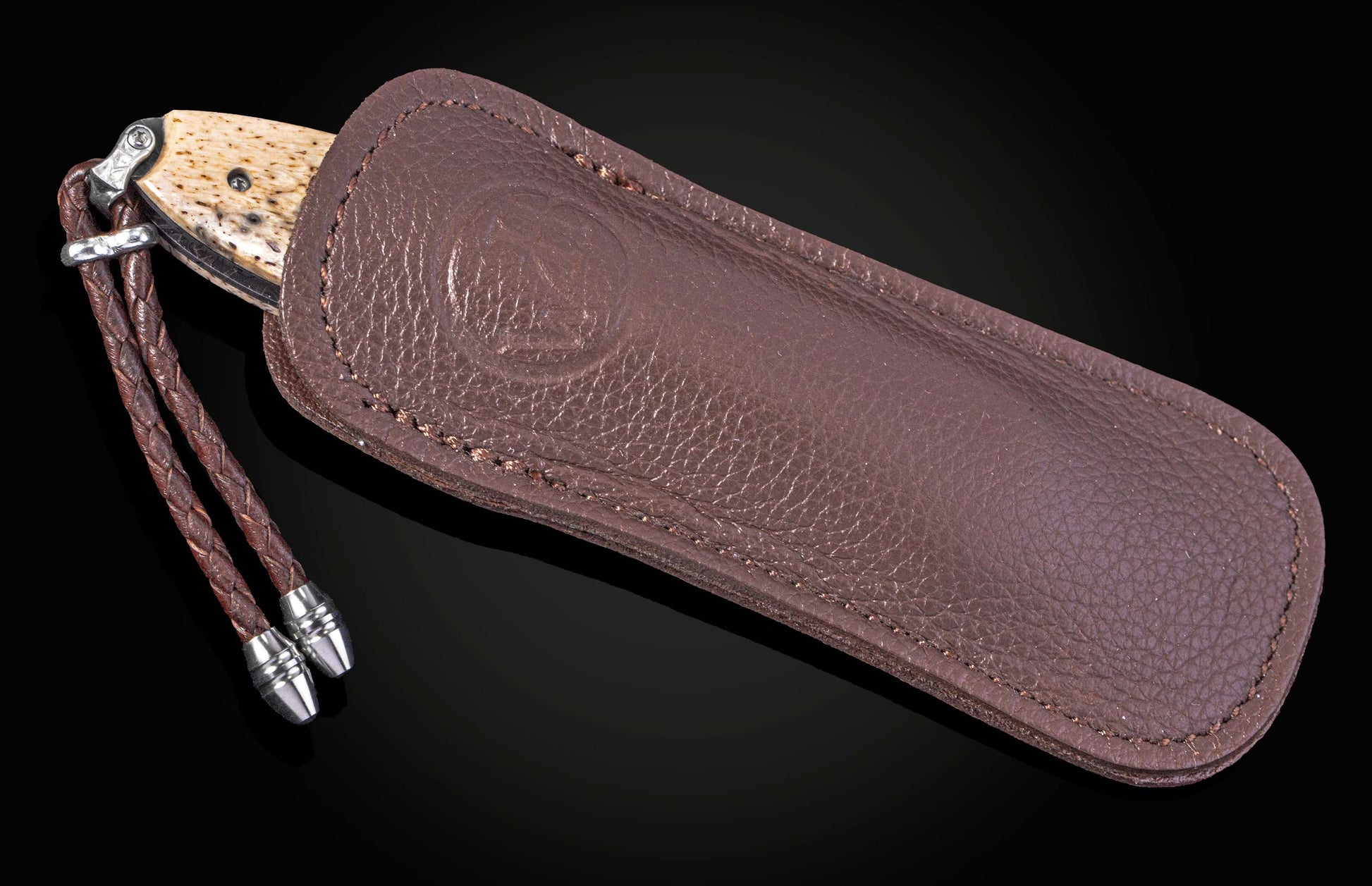 Folding knife with damascus blade and fossil walrus bone scales on a black background