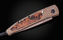 Luxury folding knife with mokume-gane handle and wood inlay, by B10 Riverwood, featuring black braided lanyard, side view on dark background