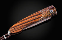 William Henry knife with zebra wood handle and damascus steel blade on a black background