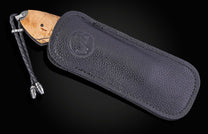 Folding knife with wooden handle and decorative blade on a black background