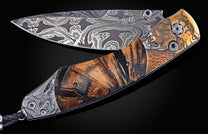 Ornate folding knife with Damascus blade, engraved leopard head, striped wood, and carved rhino pommel.
