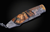 Ornate folding knife with detailed Big 5 animal engravings, a rich wood grain handle, a patterned blade, and a braided lanyard on dark background.