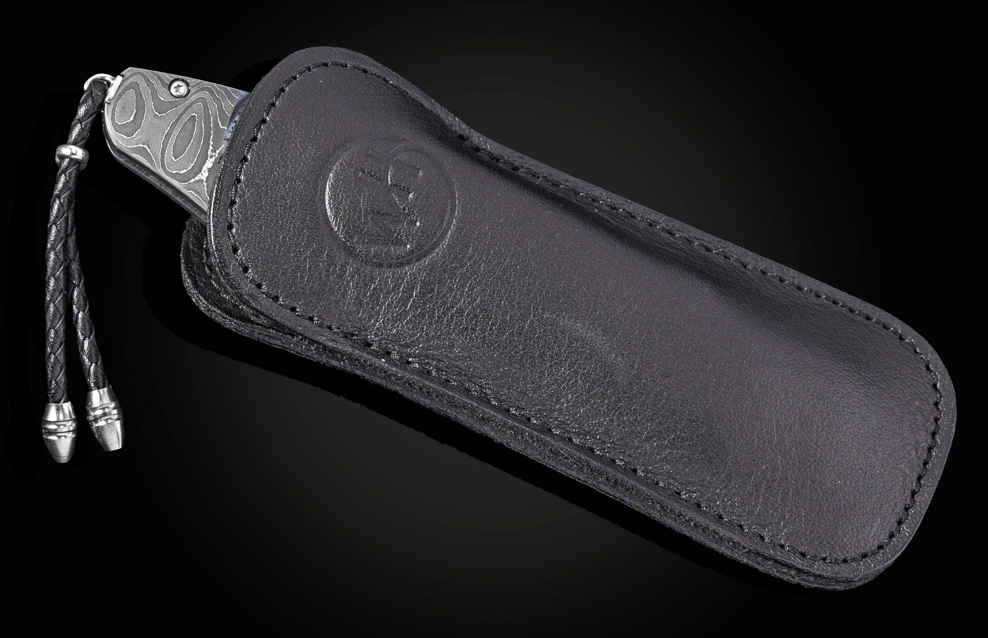 Damascus steel knife with blue meadow pattern in black leather sheath by B12, featuring braided cord and embossed logo, side view