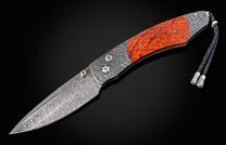 Folding knife with a decorative blade and wooden handle on a black background