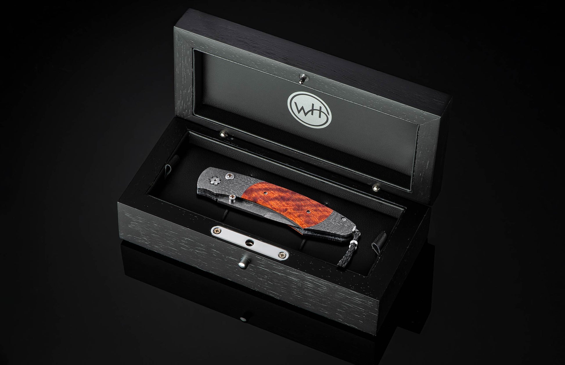 Folding knife with wooden blade in a black display box on a dark background