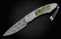 Luxury folding knife with damascus blade and green jade handle, featuring intricate Chinese dragon engravings and silver accents, side view on black background