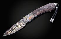 Folding knife with a Damascus blade, an engraved handle featuring a classic orange car and gears, dark wood scales with orange patterns, and a black braided lanyard.
