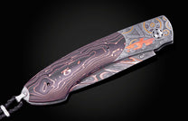 Custom folding knife with dark handle, glowing orange lines, and engraved metal featuring an orange classic Camaro and gears.