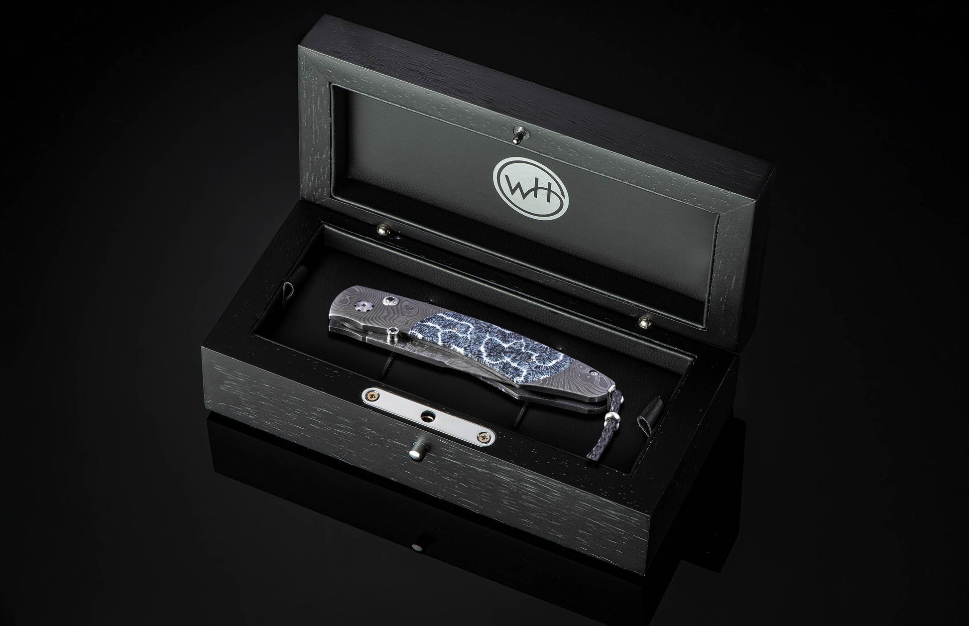 Folding knife with Damascus steel blade and fossil coral handle on a black background