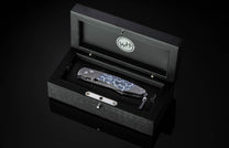 Folding knife with Damascus steel blade and fossil coral handle on a black background