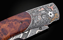 Luxury folding knife with rich wood handle and intricate silver cowboy vaquero engraving, featuring bull motifs and floral scrollwork, side view.