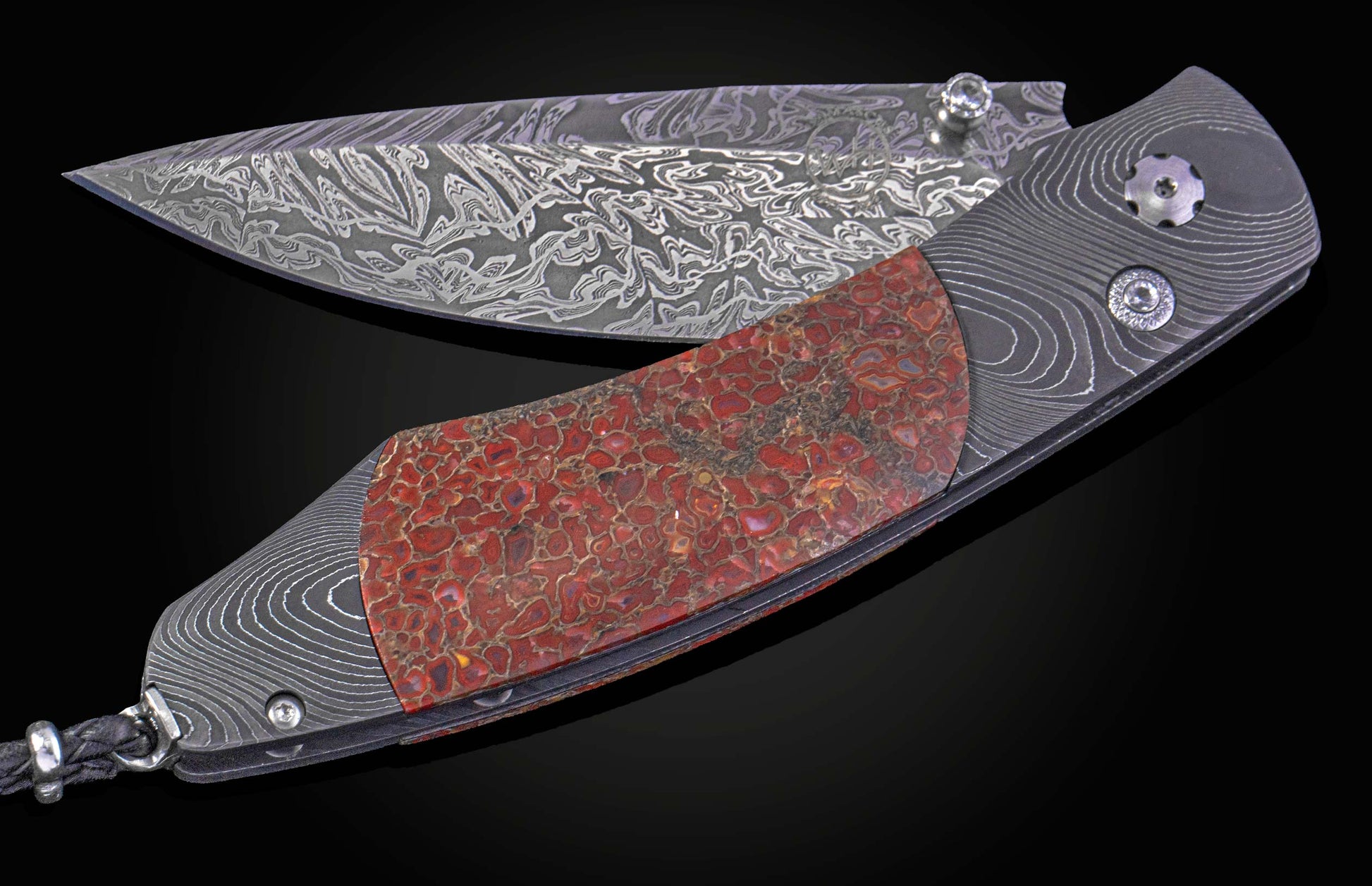 Decorative knife with a damascus blade and fossilized dinosaur bone scales on a black background