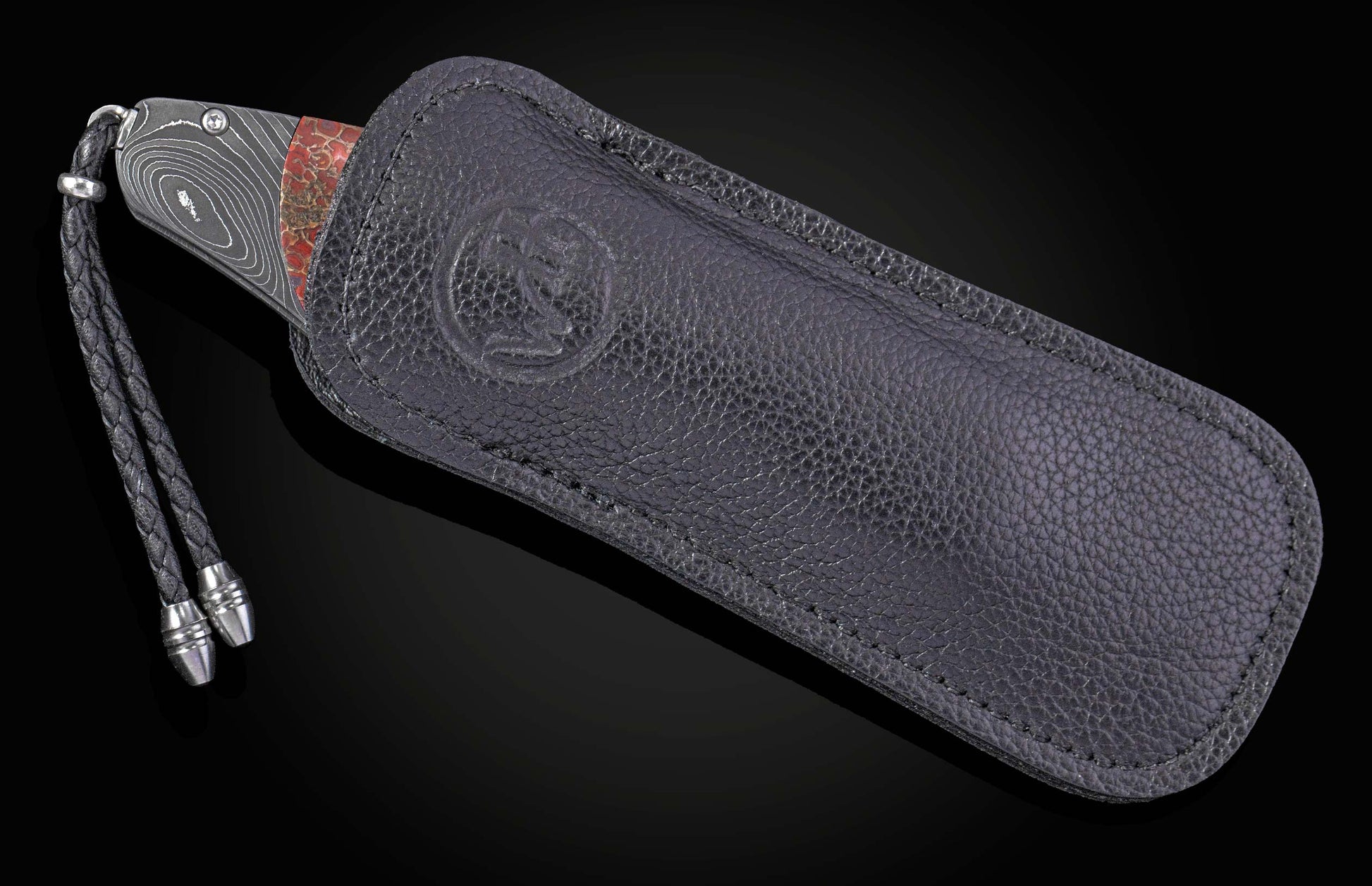 Decorative knife with a damascus blade and fossilized dinosaur bone scales on a black background