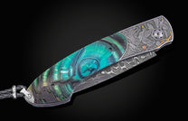 Hand engraved William Henry knife with mammoth tusk handle and damascus blade on a dark background