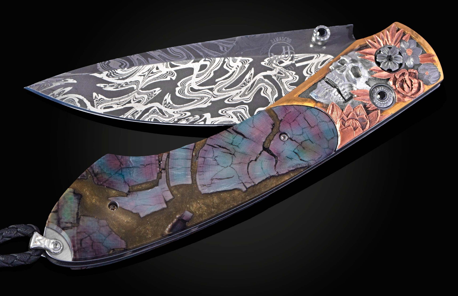 Ornate folding knife with a patterned Damascus steel blade, a floral skull motif, and a colorful cracked wood handle.