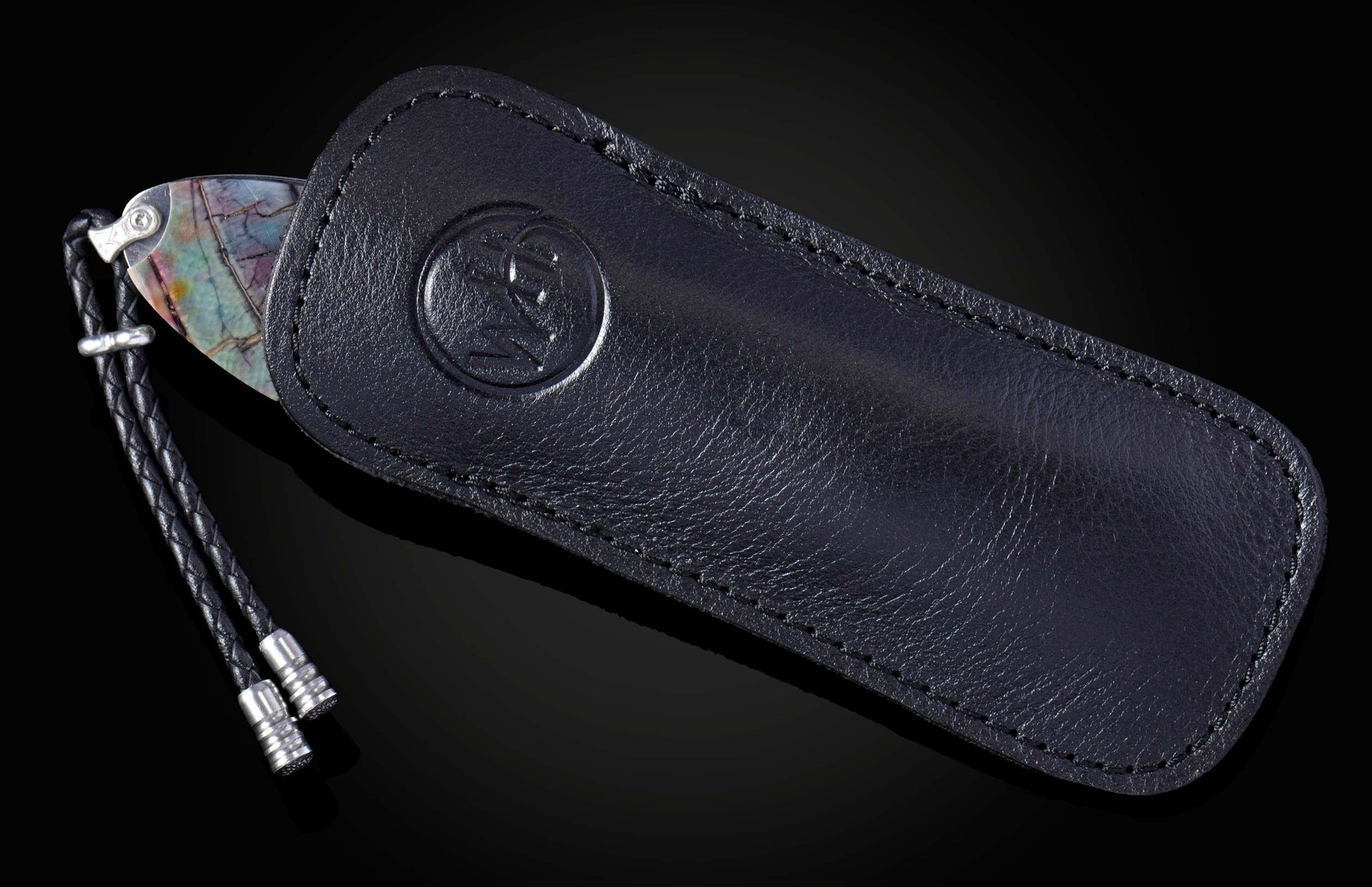 Knife with colorful veined handle partially in a black leather sheath with embossed logo and braided lanyard.