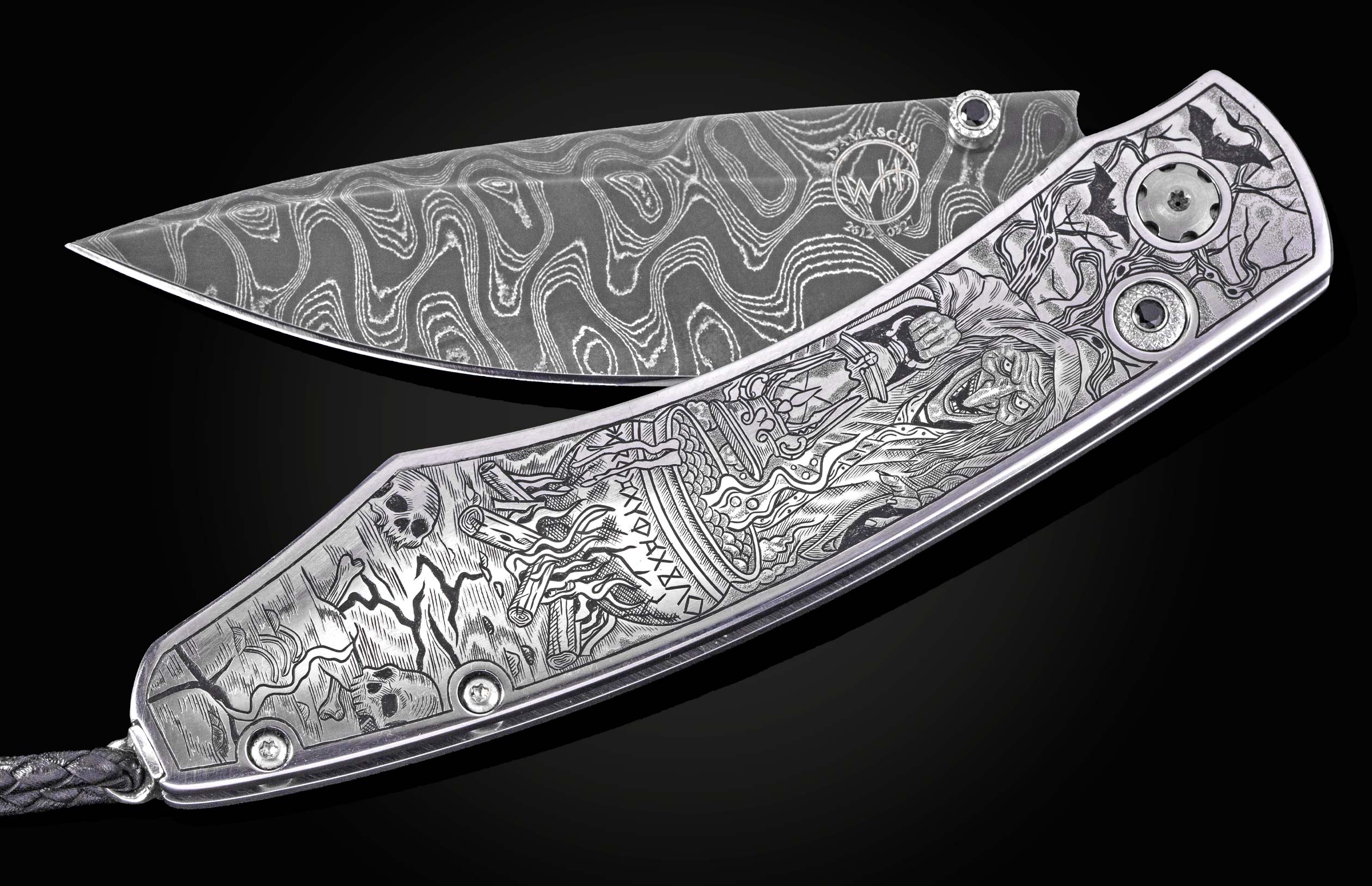 Damascus steel folding knife by B12 with intricate Halloween-themed engraving, silver-toned handle, and black gem accents, displayed open on black background