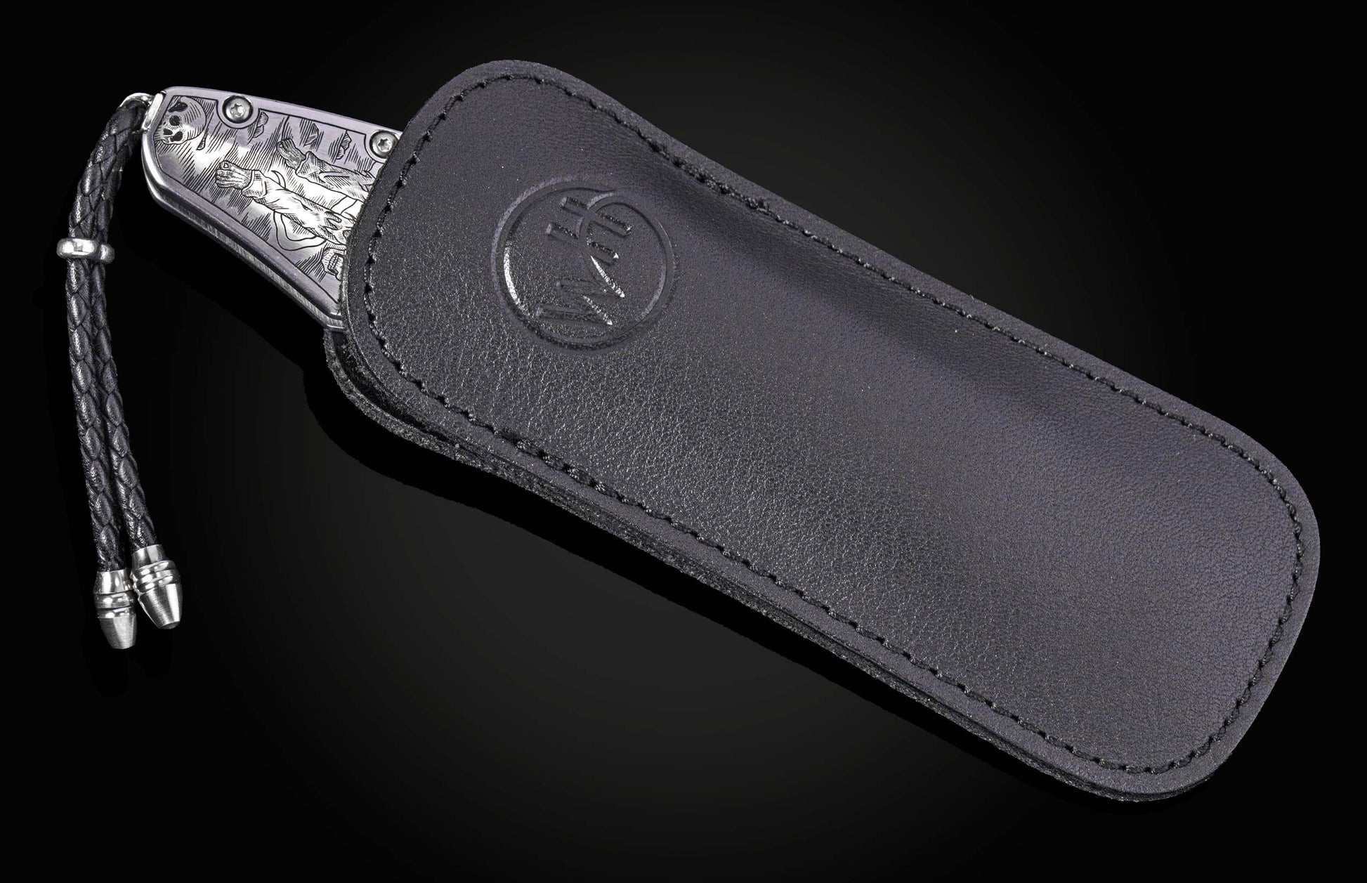 Silver engraved folding knife with Halloween-themed skeleton design, by B12, in black leather sheath with braided cord and metal tips, side view.