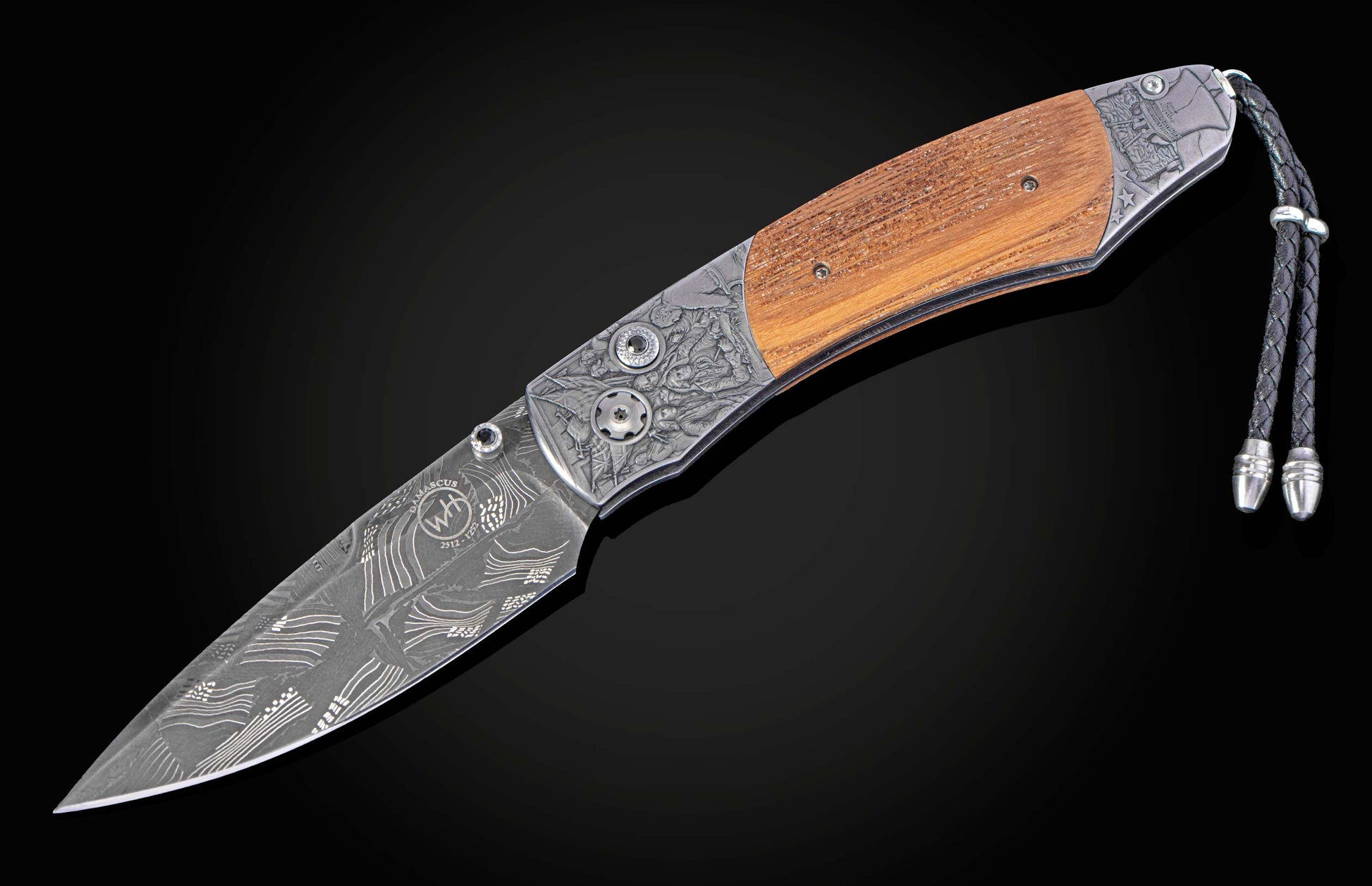 Damascus steel folding knife with a light brown wooden handle, intricately engraved metal bolsters, and a braided leather lanyard.