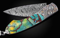 Damascus steel knife with intricate wave pattern and colorful resin handle by B12, featuring mechanical gear accents and silver hardware, side view on black background