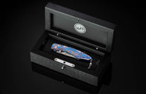 Decorative pocket knife in a black display case with WHT logo.