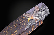 A knife with a dark wood handle and a silver-toned metal panel featuring an embossed mallard duck with gold and bronze accents, surrounded by textured foliage.