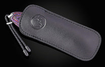 Luxury folding knife with vibrant purple and red patterned handle, by B12, in black leather sheath with embossed logo and braided cord.