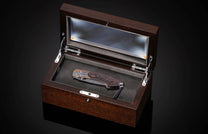 Folding knife with Damascus steel blade and hand engravings on a black background