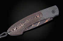Folding knife with Damascus blade and black handle on a dark background