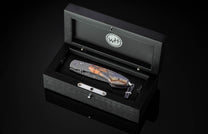 Folding knife with decorative blade and mammoth tooth handle on a black background